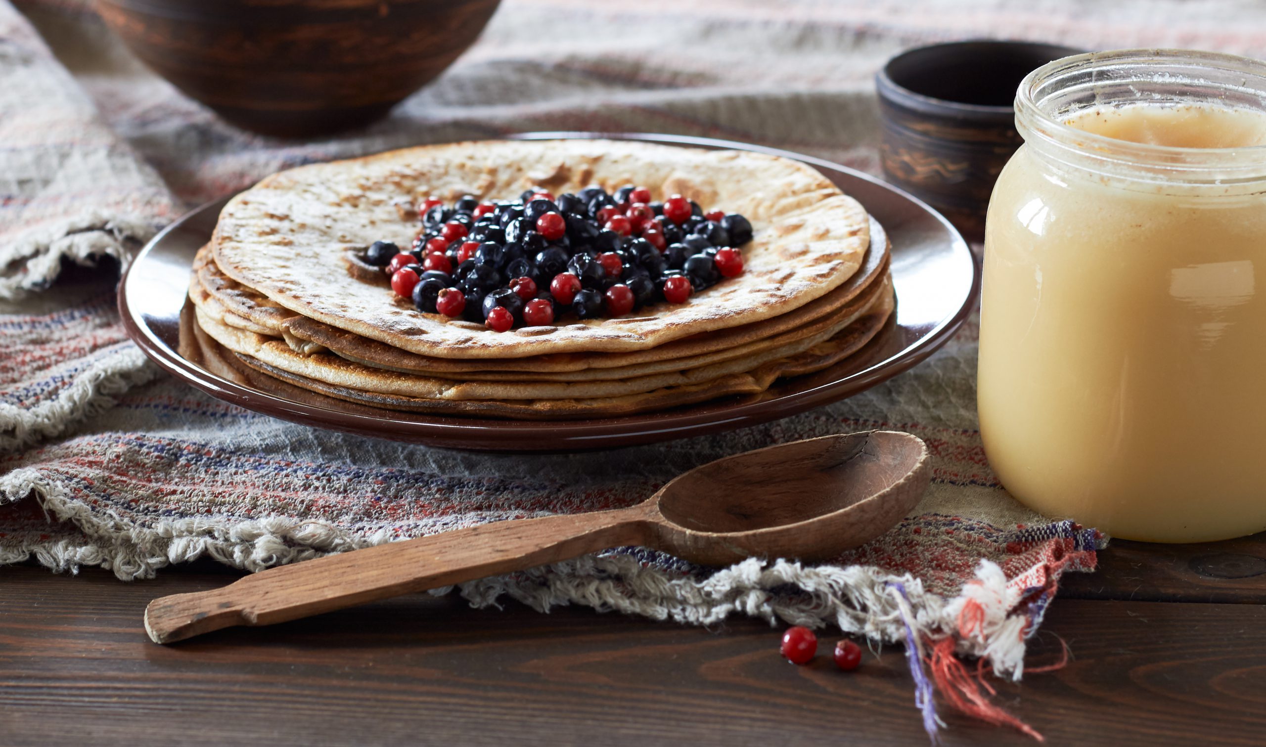 Pancake week hot cakes with berries, honey and butter on rustic background, closeup, copy space, shrovetide and homemade food concept