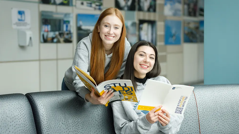 Two student girls looking brouchures and smiling